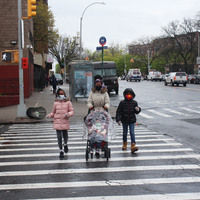 A family with masks on walking on a cross walk.