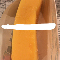This is a picture taken of an orange ice cream pop in a wrapper. 