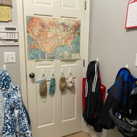 Masks and backpacks hanging on a door. 