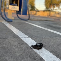 This is a picture of a discarded face mask resting on the ground at what appears to be a gas station. 
