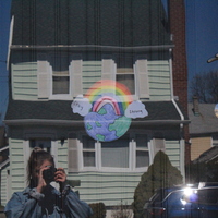 Residential house with a rainbow in the front door with the words "stay strong" on both ends and the world behind it. 