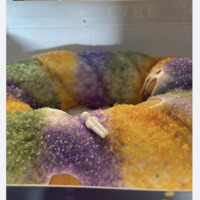 Screenshot of Facebook post. Image is of a king cake with miniature baby lying on top. Text reads, "Impulse purchase: let there be cake". 