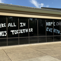 Window writing reading "We're All In This Together. Hope Changes Everything".