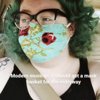 A screenshot of a social media post featuring a woman wearing a mask. The words on the picture reads "modern musings: I should get a mask basket for the entry way".