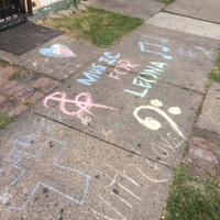 "Music for Leona" written on the sidewalk with chalk. 