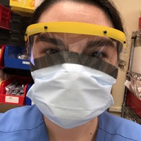 A nurse wearing a face mask and a clear eye covering.