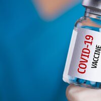 This is an image of a small glass bottle  labeled "COVID-19 Vaccine".