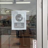a sign on a glass door telling people masks are required
