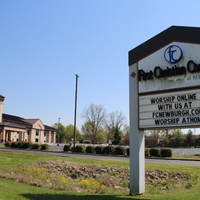 A church sign reading "Worship online with us at fcnewburgh.com worship at home".