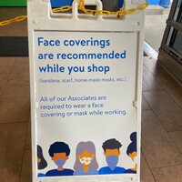 A sign reading "Face Coverings are Recommended While You Shop".