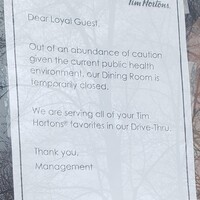 A sign at Tim Hortons reading "Dear Loyal Guest, Out of an abundance of caution given the current public health environment, our dining room is temporarily closed. We are serving all of your Tim Hortons favorites in our drive-thru. Thank you, management."