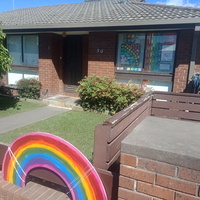 Picture of a home with windows and a fence decorated with rainbow patterns. 