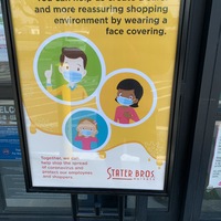 Image of a mall sign that says you can help us create a safer and more reassuring shopping environment by wearing a face covering.