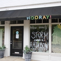 A store window reading "After Every Storm Comes a Rainbow".